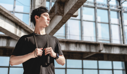 年轻男子双手拿着跳绳挂在脖子上