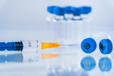 蓝色背景下的疫苗瓶和注射器