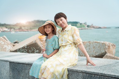 夏天坐在海边玩耍的中国母女