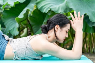 一位年轻女性在荷花池边练习瑜伽