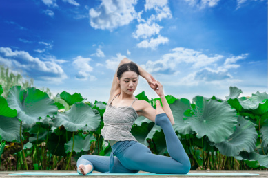 一位年轻女性在荷花池边练习瑜伽