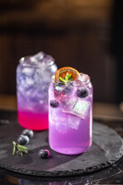 暗色桌面上放着一杯紫色鸡尾酒