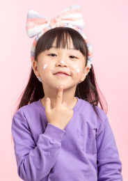 在脸上涂抹护肤霜的孩子