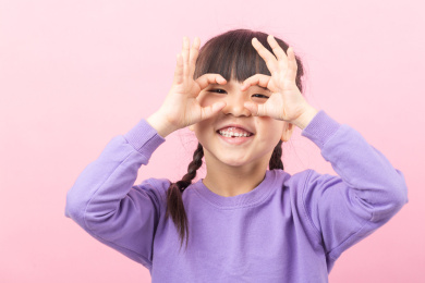 粉色背景前可爱的亚洲小女孩