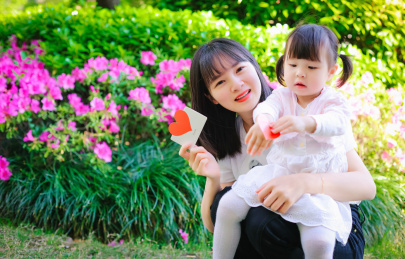 美丽的妈妈抱着孩子在公园里感受春天