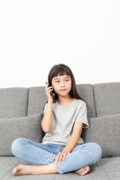 客厅沙发上一个中国小女孩在玩手机