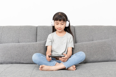 客厅沙发上一个中国小女孩在玩手机