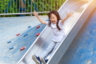 户外游乐场里玩滑梯的亚洲小女孩