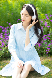 公园草地上一名年轻女性在听音乐