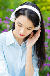 公园草地上一名年轻女性在听音乐