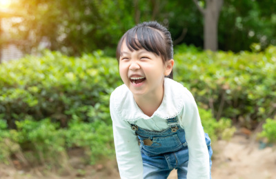 户外玩耍的小女孩开心的笑弯了腰