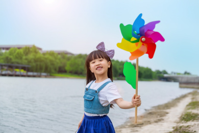 在河边玩耍手拿风车的小女孩