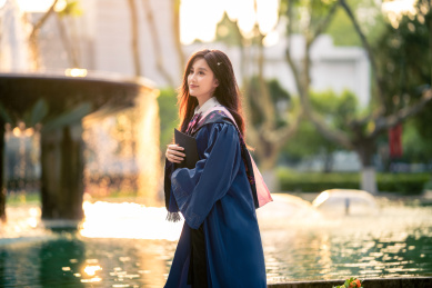 手拿着帽子身穿学士服的漂亮女生