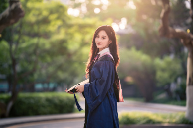 手端着帽子身穿学士服的漂亮女生