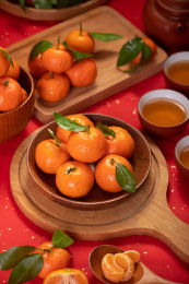 红色背景前装在木盘中的砂糖橘水果